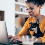woman with dog in lap sitting at computer