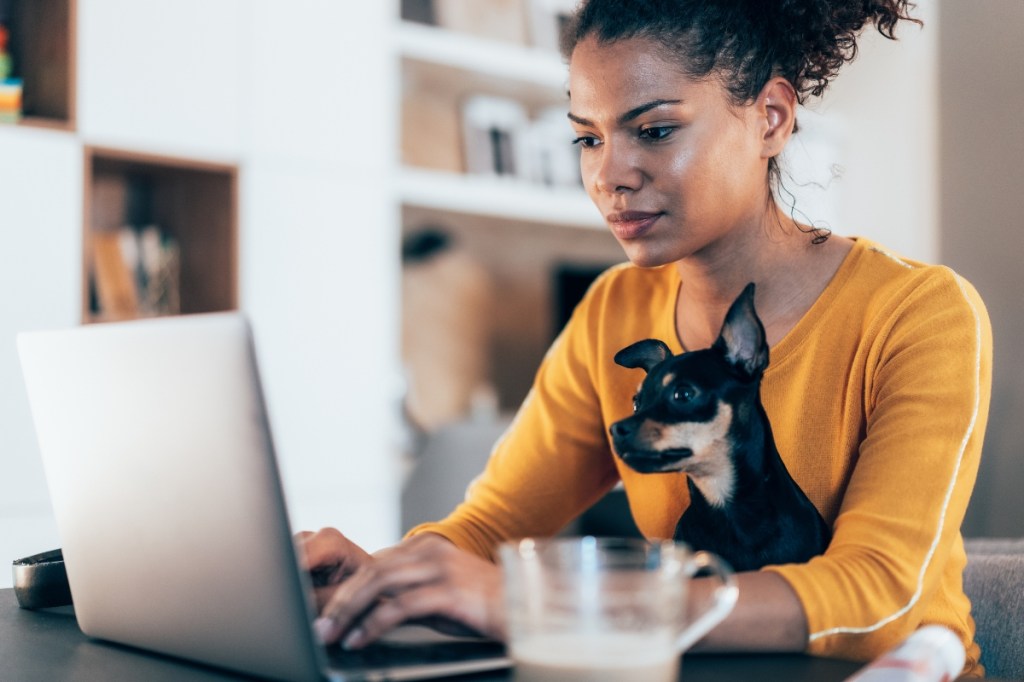 woman with dog in lap sitting at computer