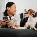 Woman holding phone next to dog