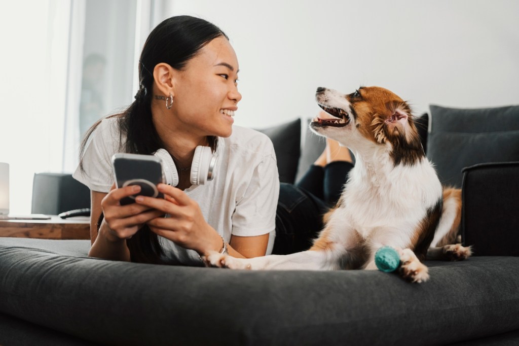 Woman holding phone next to dog