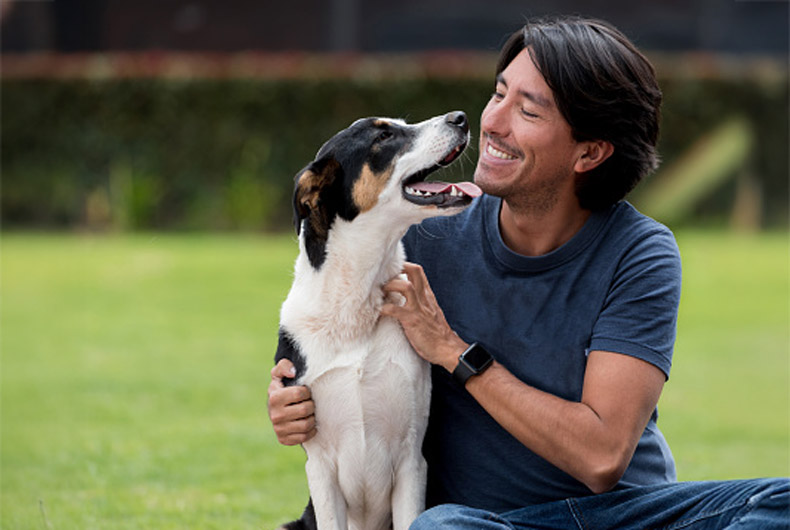 man sitting outside with dog smiliing at each other